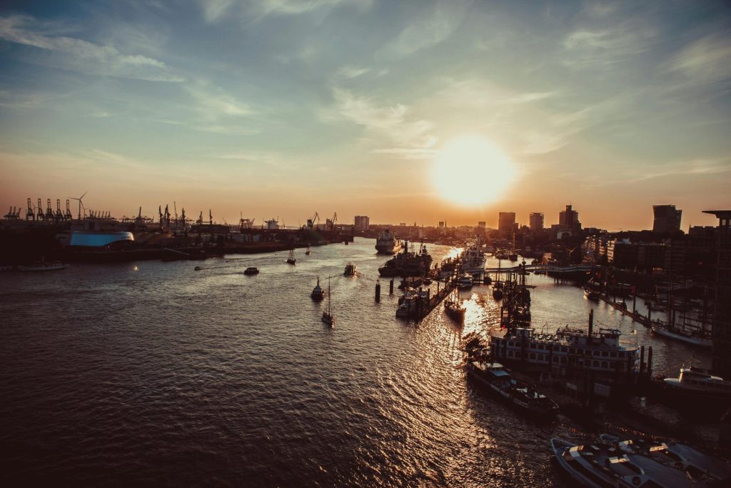 Ein atemberaubender Blick auf den Hamburger Hafen bei Sonnenuntergang, mit Booten und der Skyline als Silhouetten.